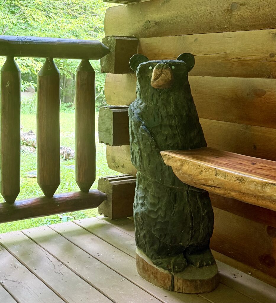 Bear sculpture holds up a bench in a log cabin